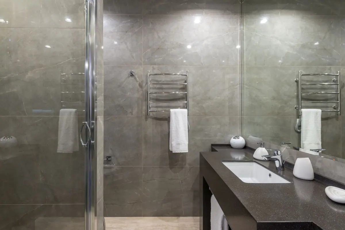 Baño contemporáneo en tonos grises con ducha de vidrio y bacha sobre mesada